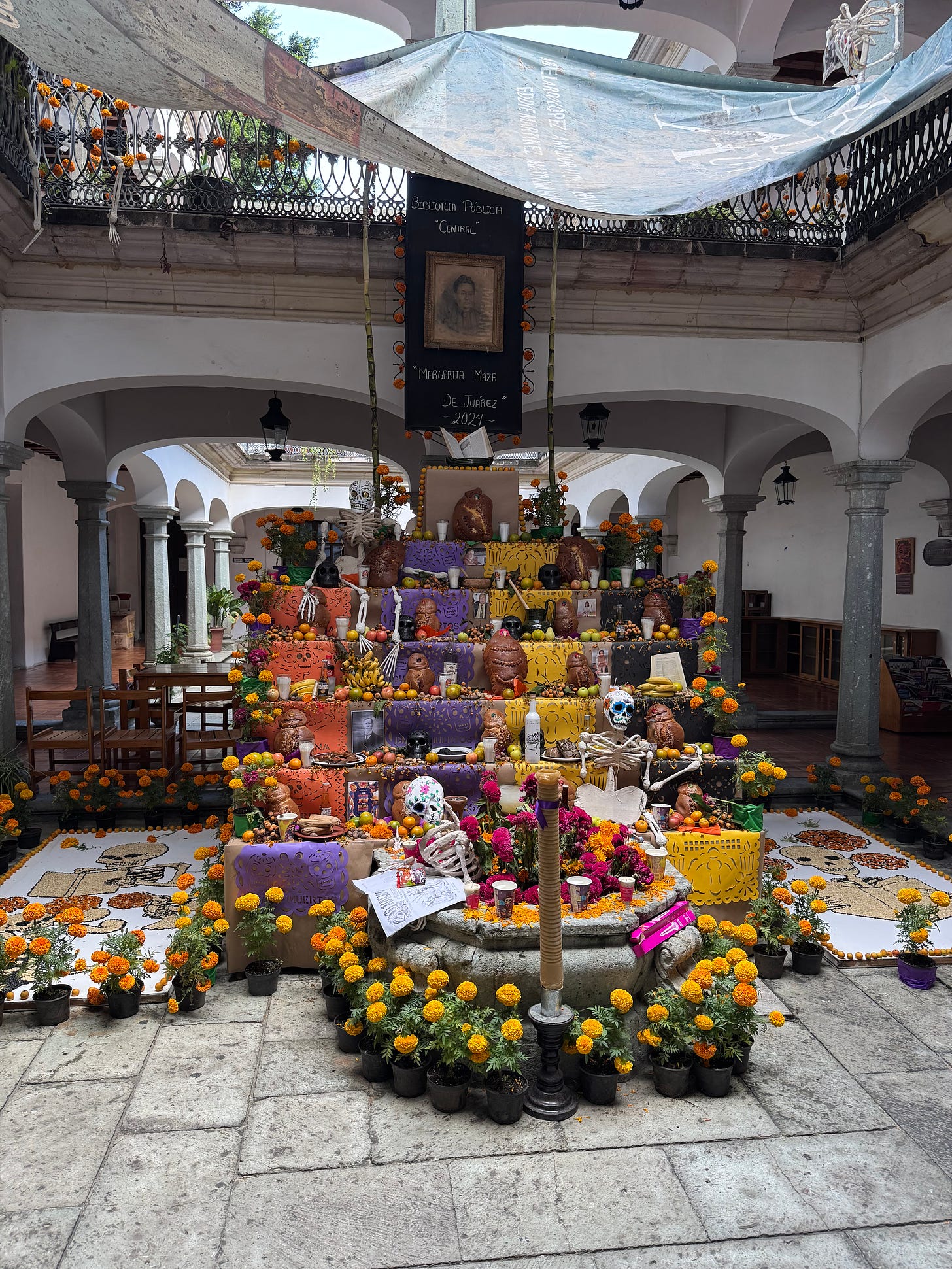 The ofrenda set up at Oaxaca’s main public library. It shows multiple tiers set with flowers and decorations.