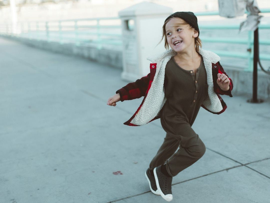 woman in black jacket and white pants sitting on concrete floor during daytime