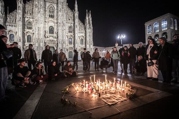 People gathered around candles and flowers outside a cathedral in Milan.