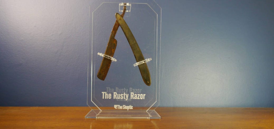 a rusty razor in a glass award case, with "the rusty razor" etched on the front