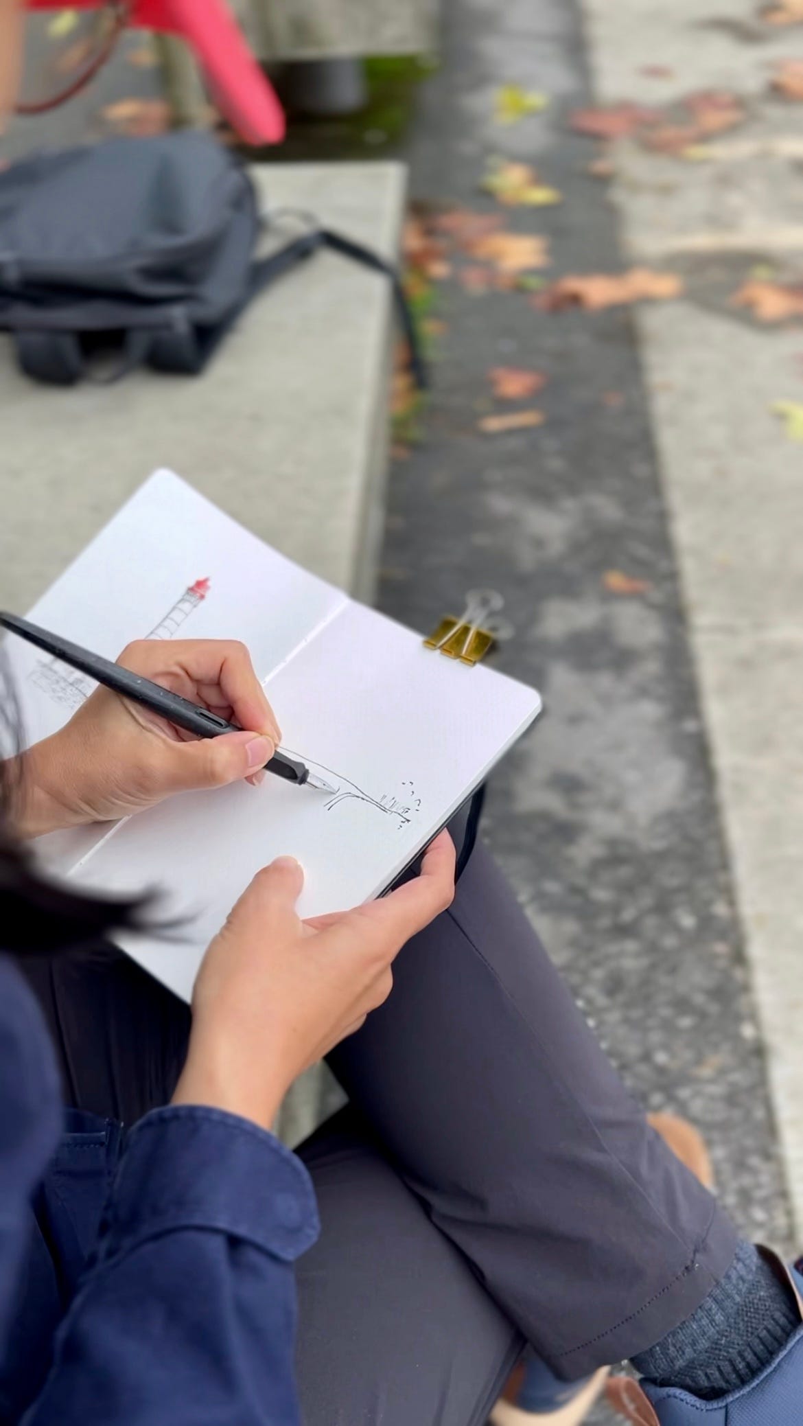image: close up photo of me with my calligraphy pen drawing on my sketchbook outdoors
