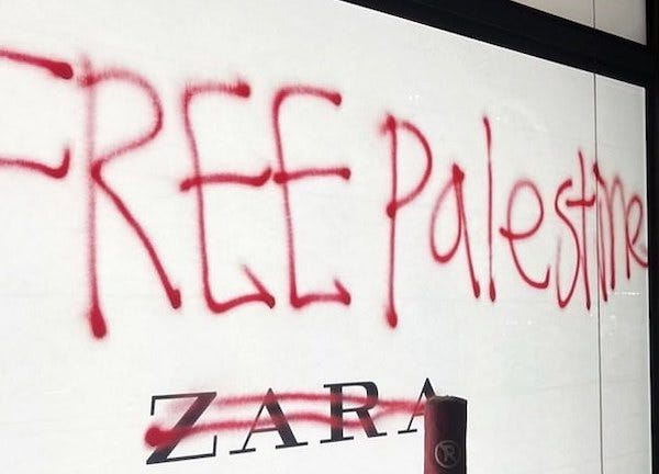 A white wall with the Zara logo is painted over in red spray paint with "Free Palestine"