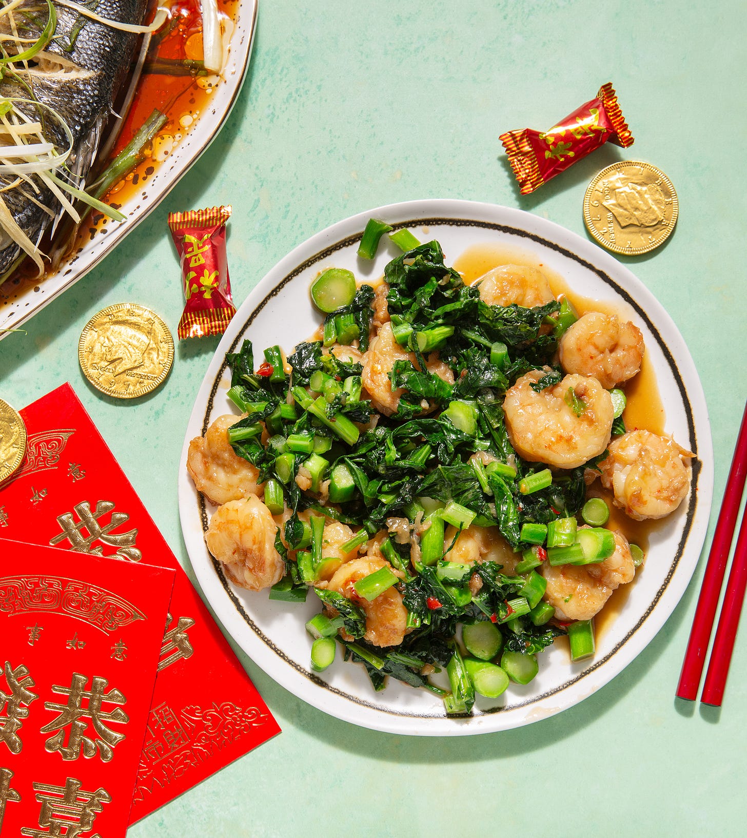 plate of shrimp with gai lan, shown with red envelope and steamed fish.