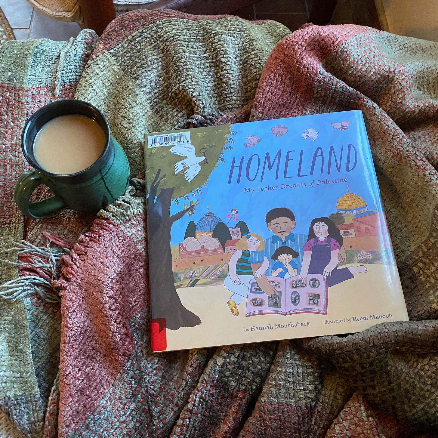 Homeland on a blanket next to a green ceramic mug of tea.