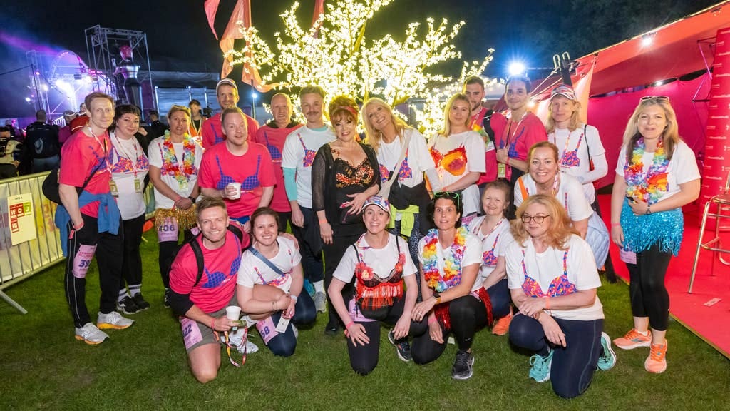 Group of men and women wear decorated bras or t-shirts with printed lingerie for charity event