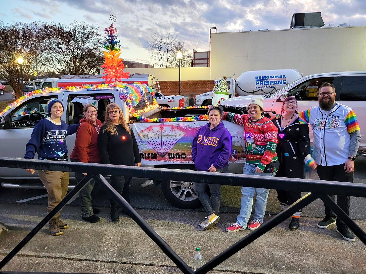 Several members of PRISM WNC standing in front of a truck decorated for Morganton's annual Holiday Parade.