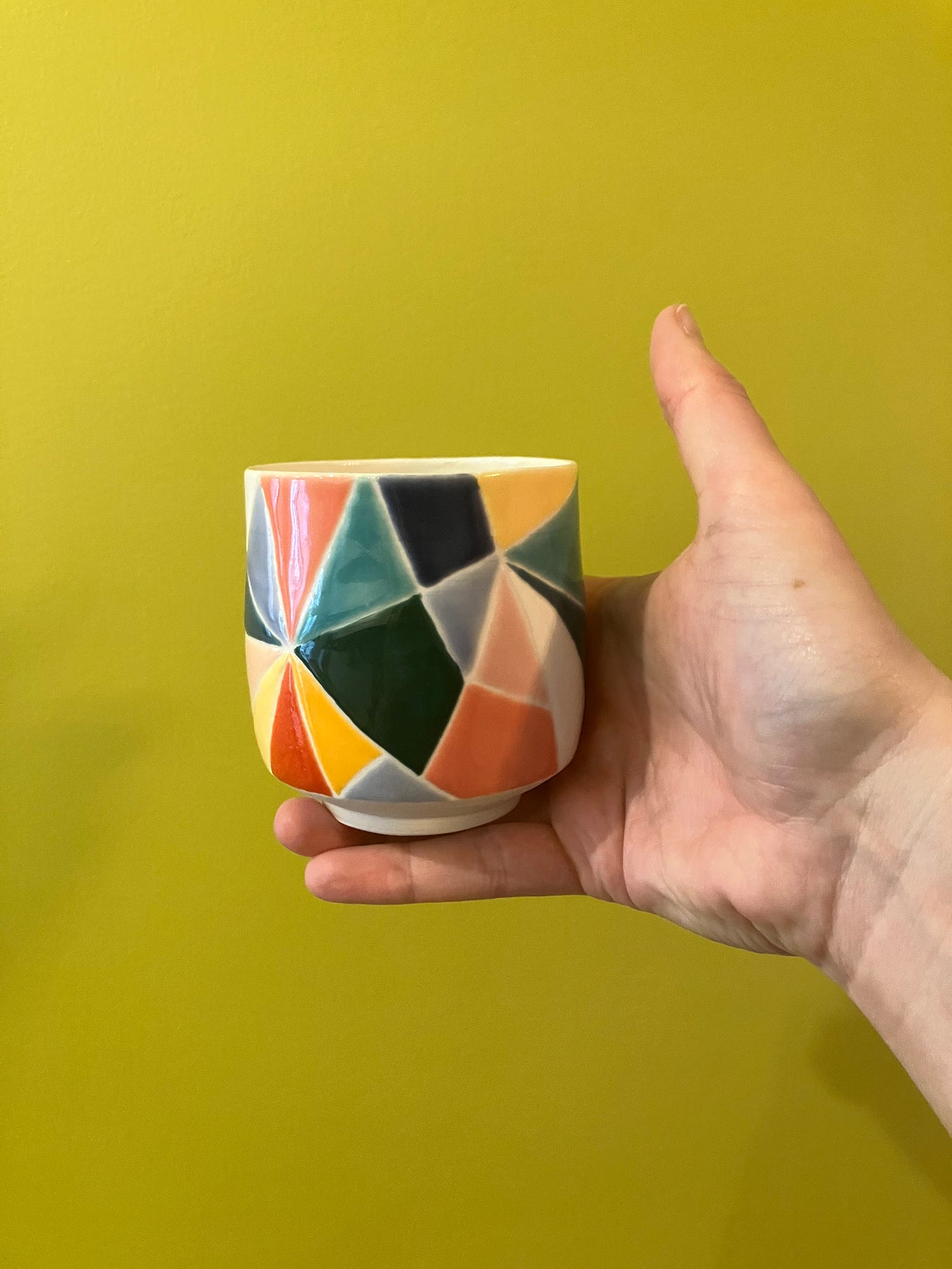 multicolored porcelain cup decorated like stained glass in hand