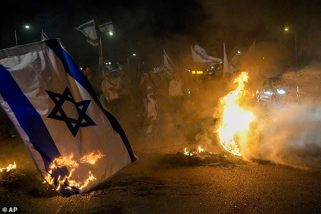 Anti-government protestors burn tires and a flag  near Beit Yanai, Israel