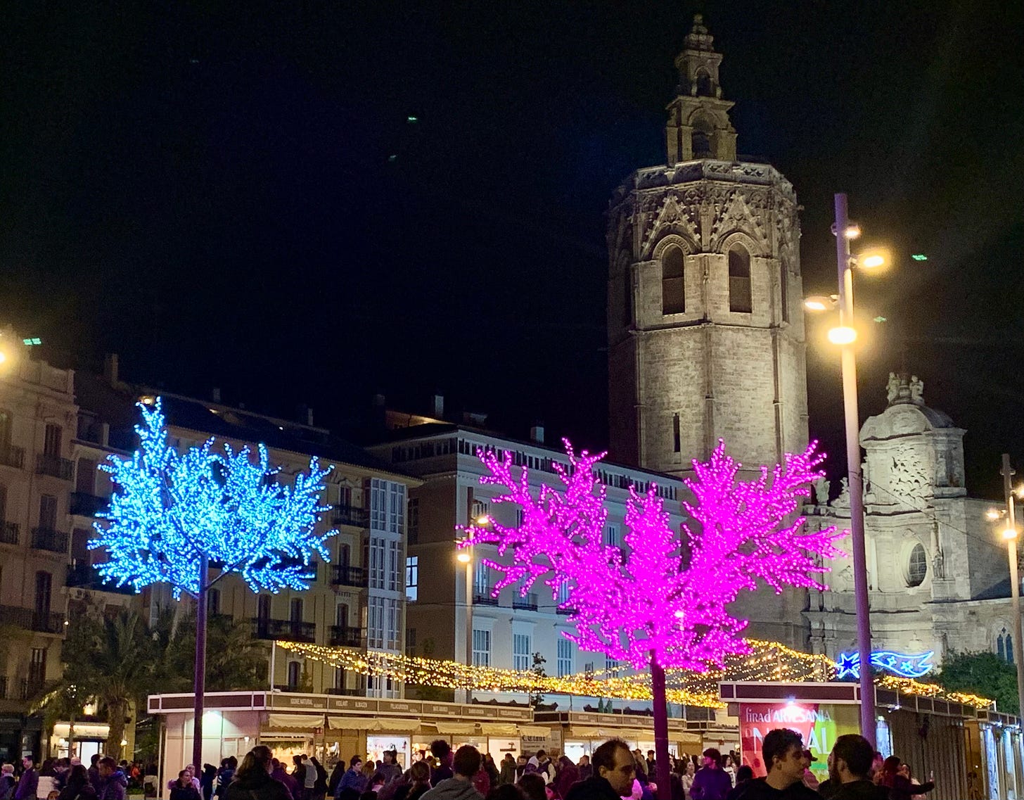 The Cathedral sits behind a small pop up market and festive lights, including trees whose leaves are all lights in white or pink.