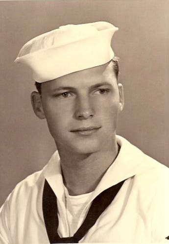 A black and white photo of a handsome young white man in a white Navy uniform.