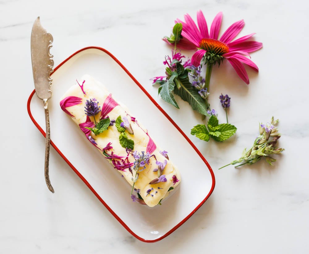 Homemade butter with edible flours on a butter dish with an antique butter knife.