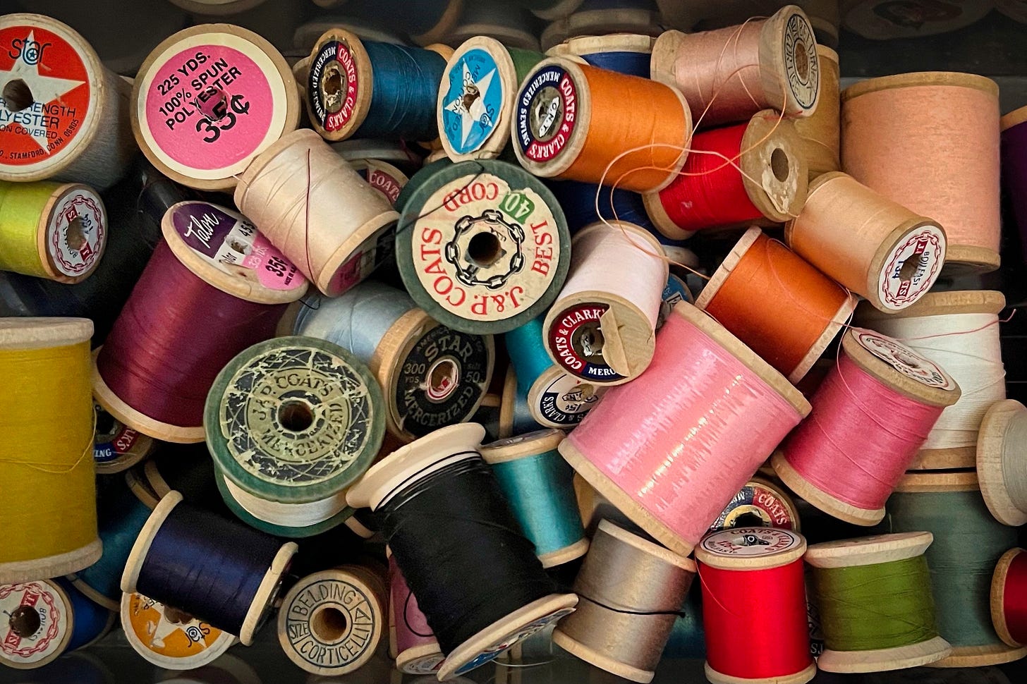 A jumble of sewing thread spools in a variety of colors 