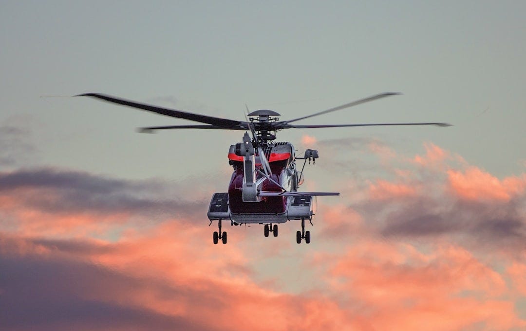 red and white hovering helicopter in mid-air photography