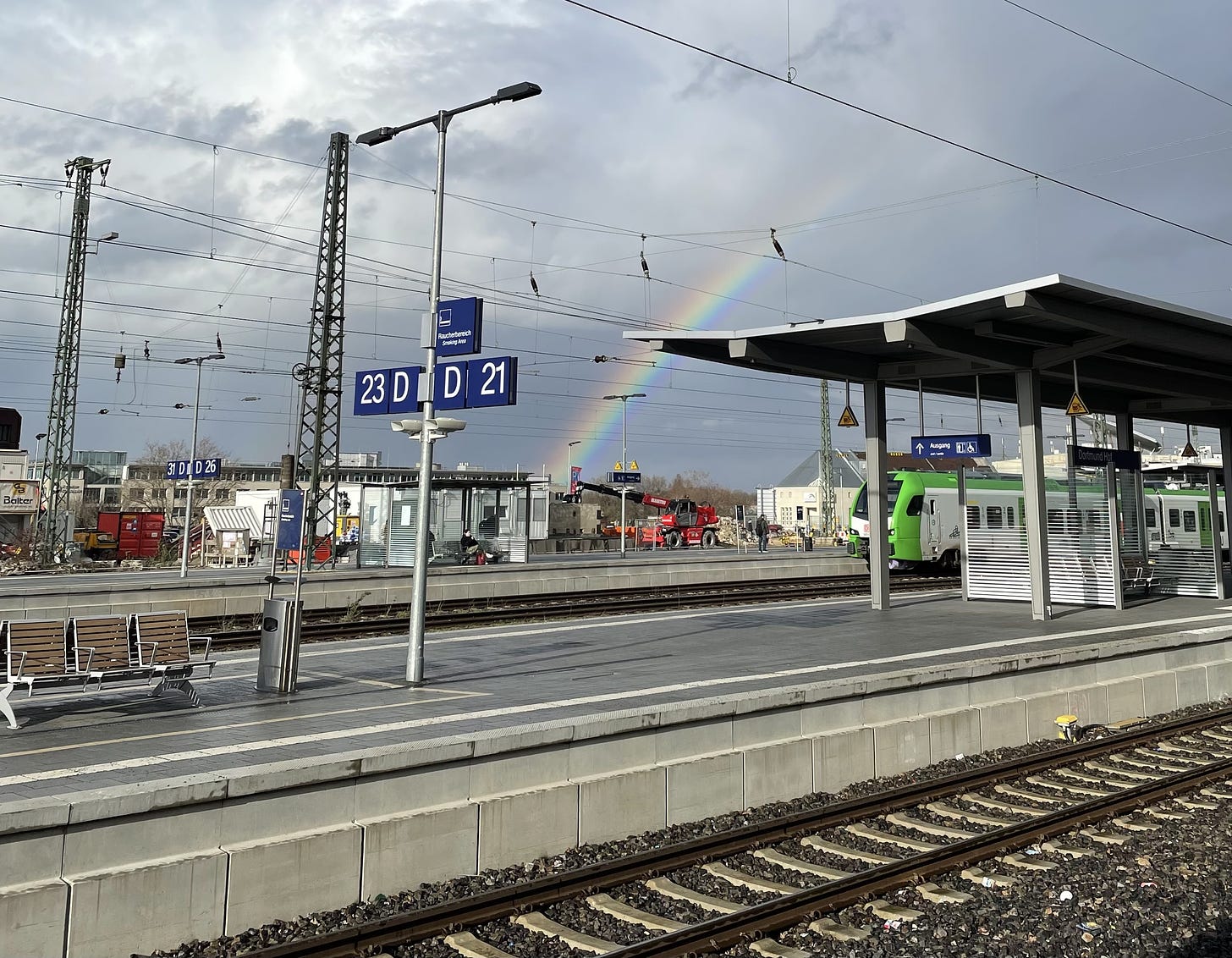 a train platform with a rainbow over it