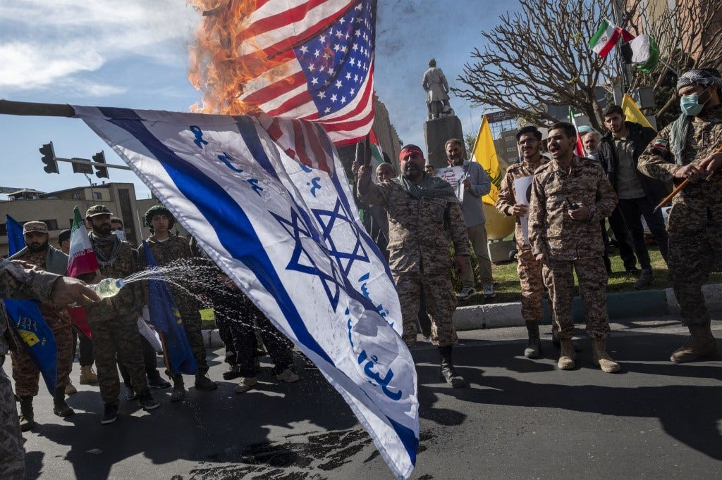 Members of the Islamic Revolutionary Guard Corps (IRGC) are burning flags of Israel and the U.S..