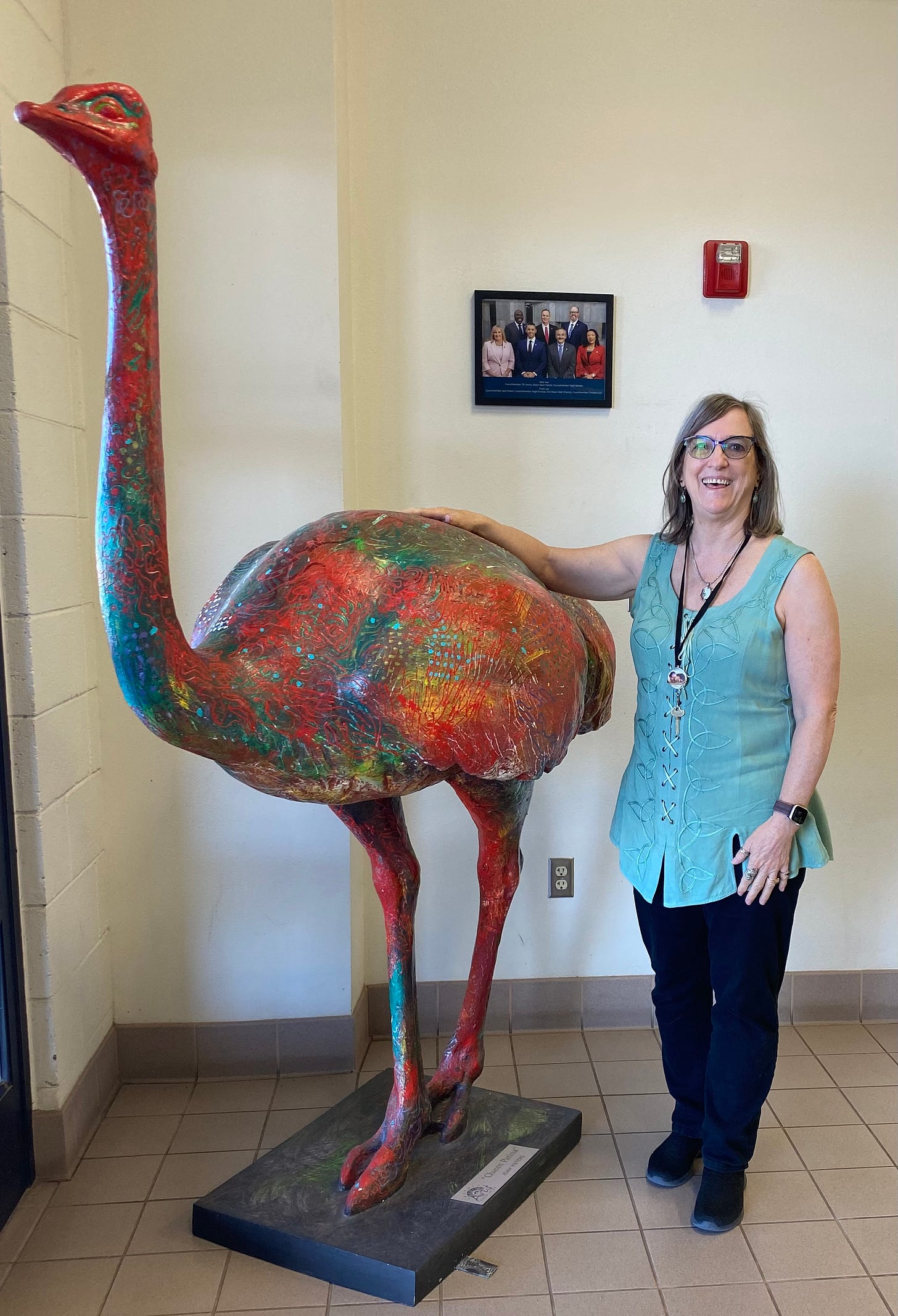 Sharon standing beside a coloful ostrich stature inside the Chandler Library Basha Branch.