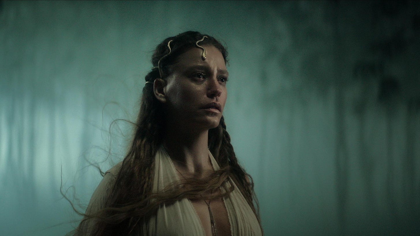Serenay Sarikaya as Sahsu in Shahmaran wears a white dress and a gold snake crown while her hair blows in the wind.