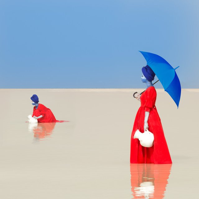A stylized image of two women in red dresses standing in a lake and gathering water into white jars