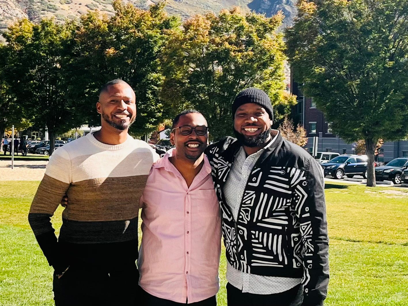 A photograph of three Black men smiling really hard.