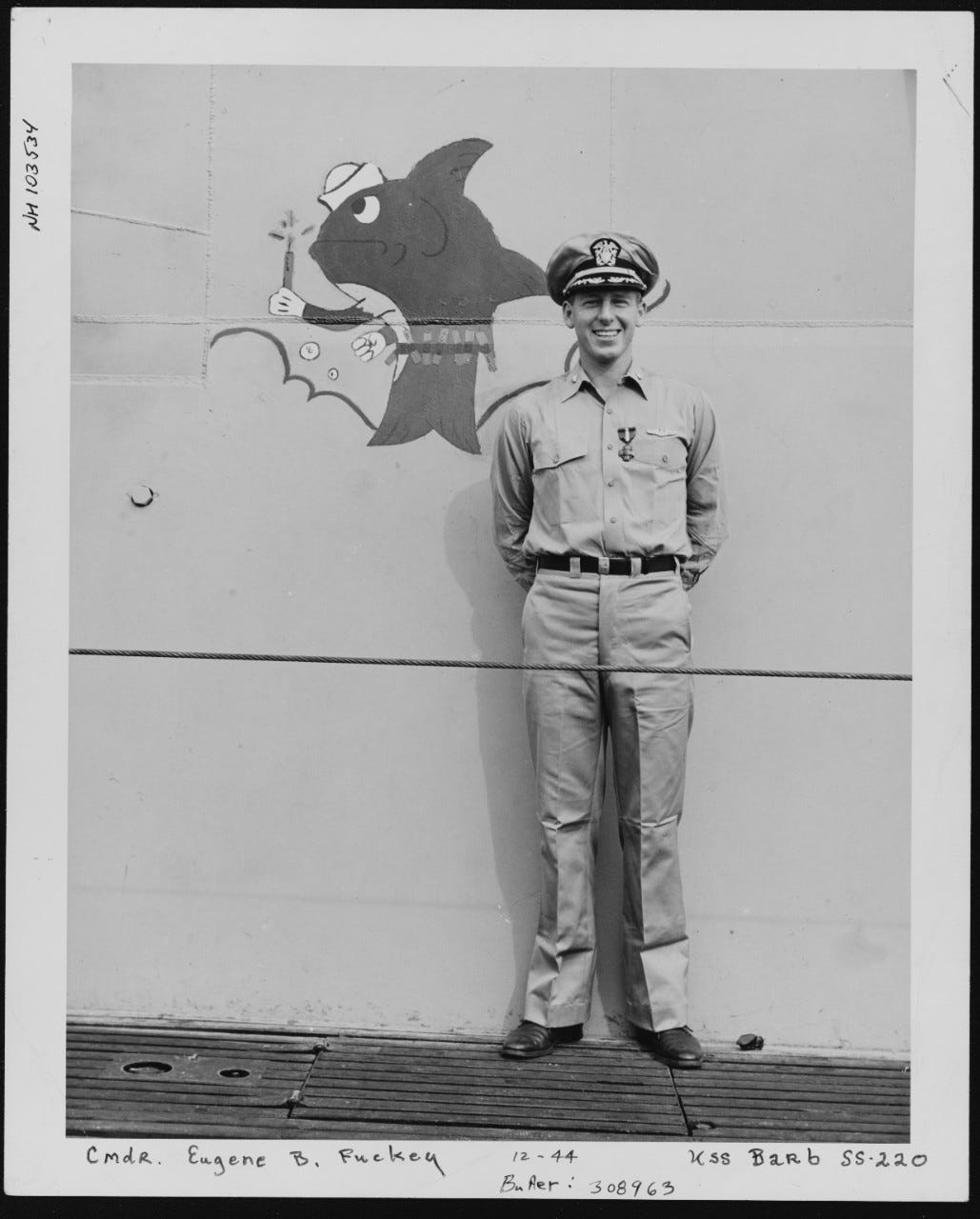 Navy description: Commanding Officer, USS Barb (SS-220) Wearing the Navy Cross on board Barb after receiving the medal from Commander, Submarine Force, Pacific Fleet, 6 December 1944. Note Barb's insignia painted on her fairwater, behind Commander Fluckey.