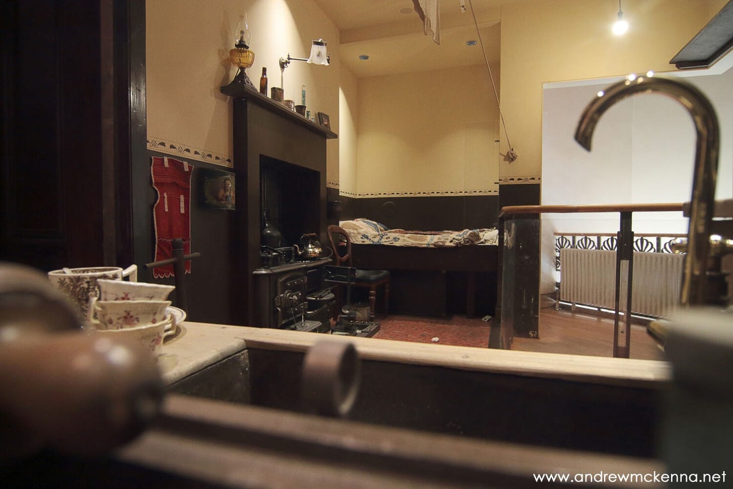 recreated interior of a tenement house with bed, fireplace and basin