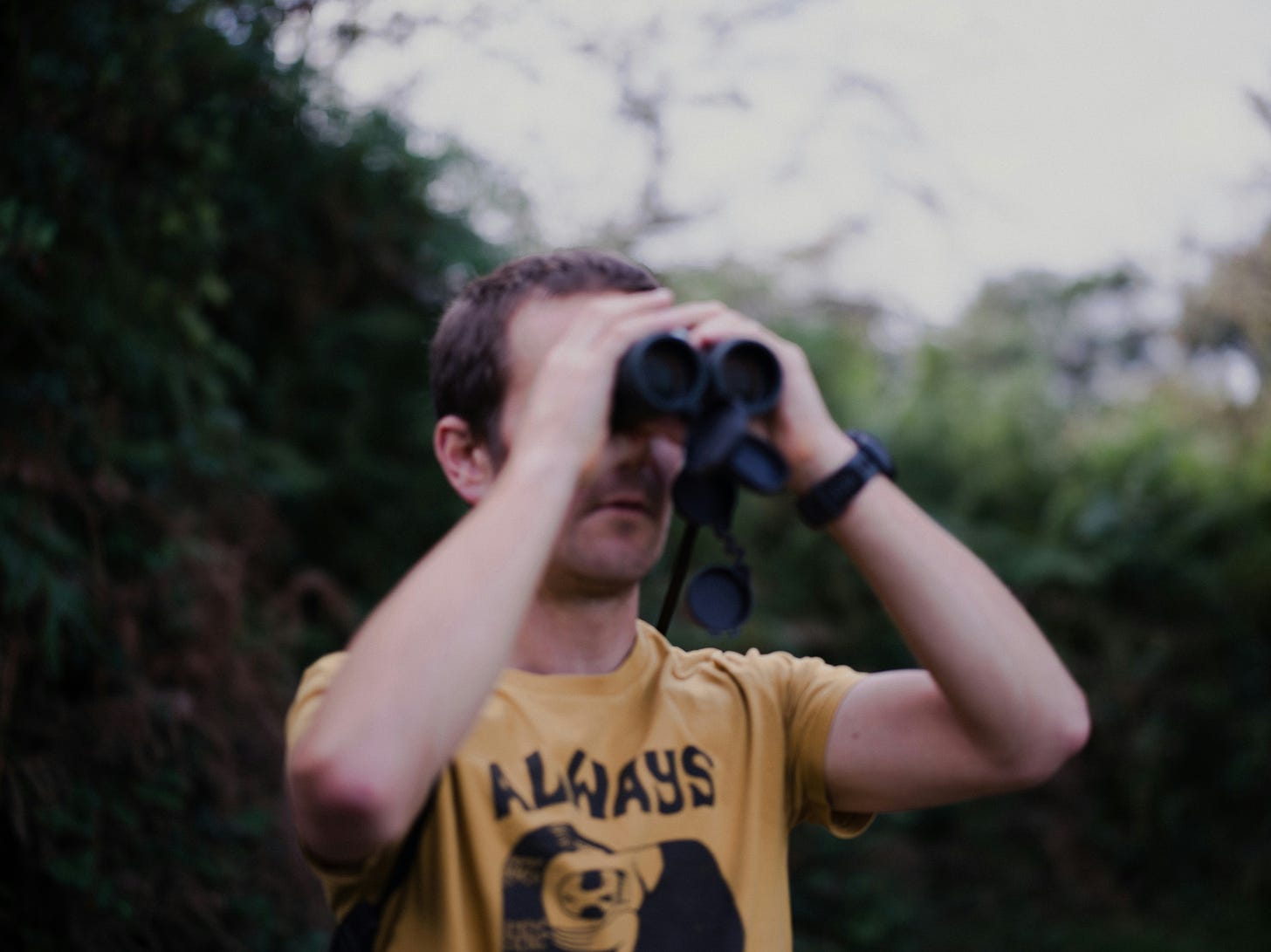 A Man in a Yellow Shirt Using Binoculars