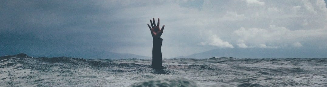 photo of person reach out above the water