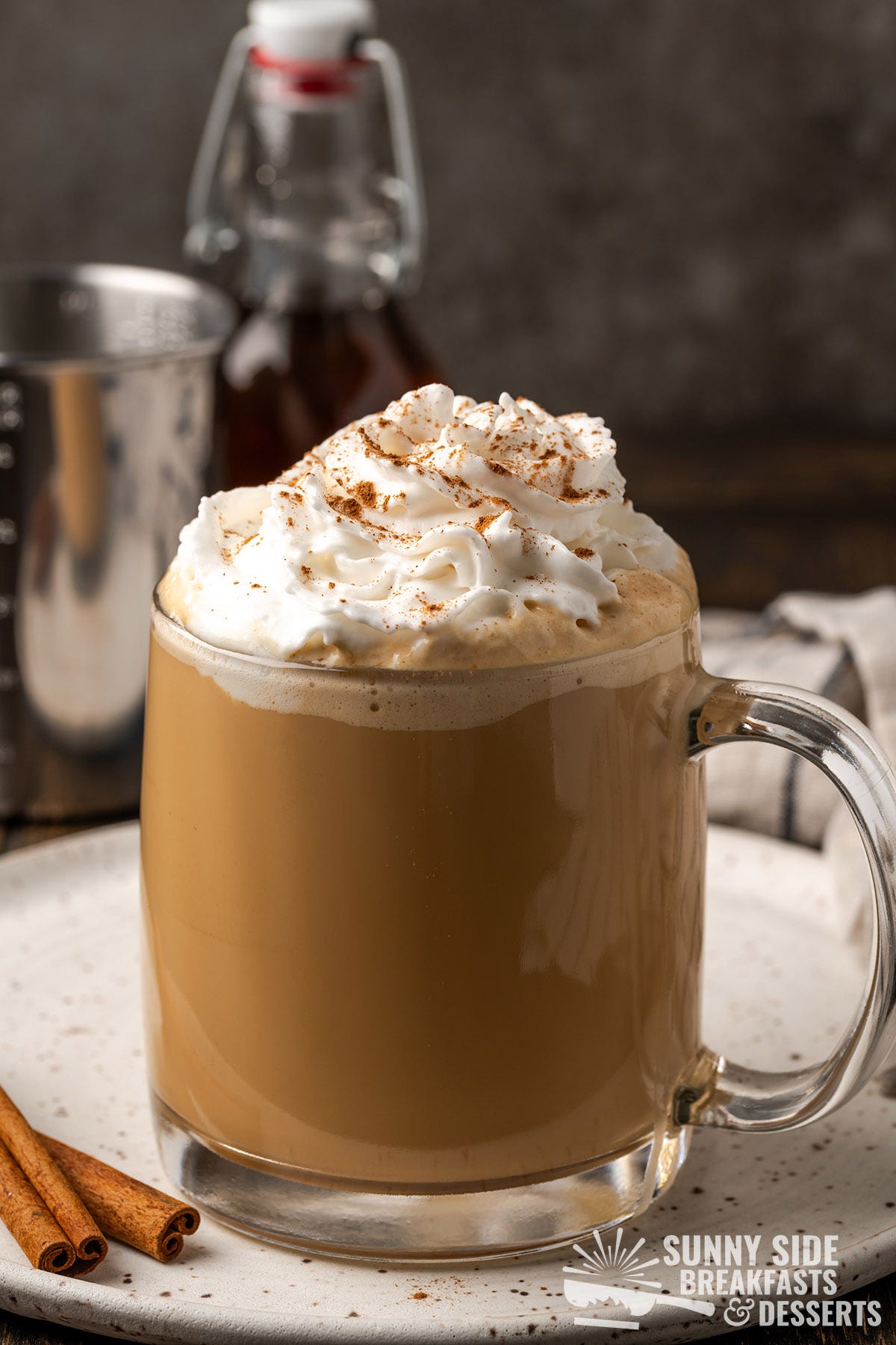 A glass of cinnamon latte with whipped cream.