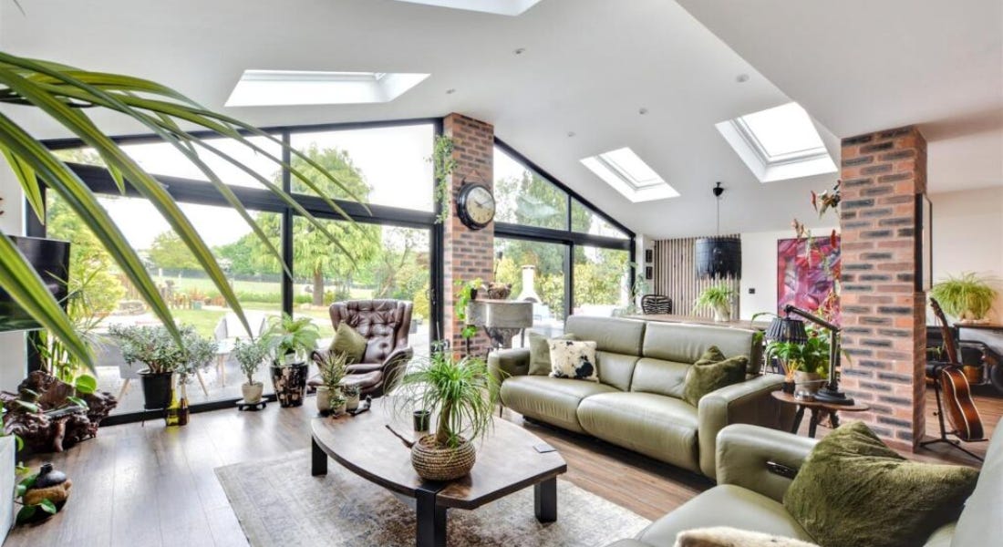 A white and black living room with seating and tropical plants decorating it