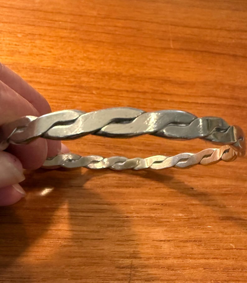 May include: A silver braided bangle bracelet.