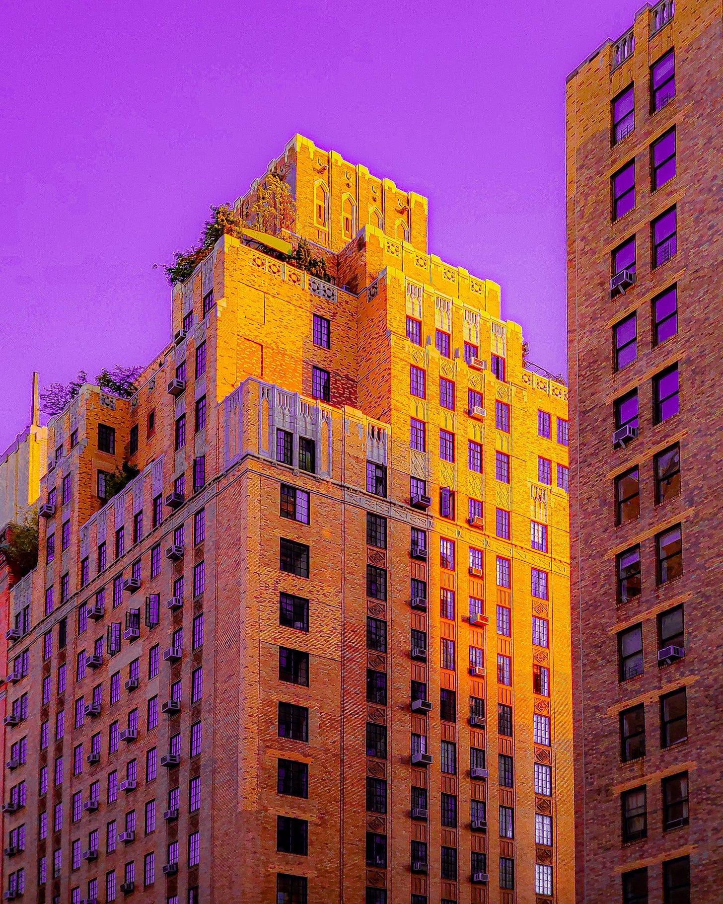 a large brick apartment building in new york city with the sky and all the windows tinted purple.