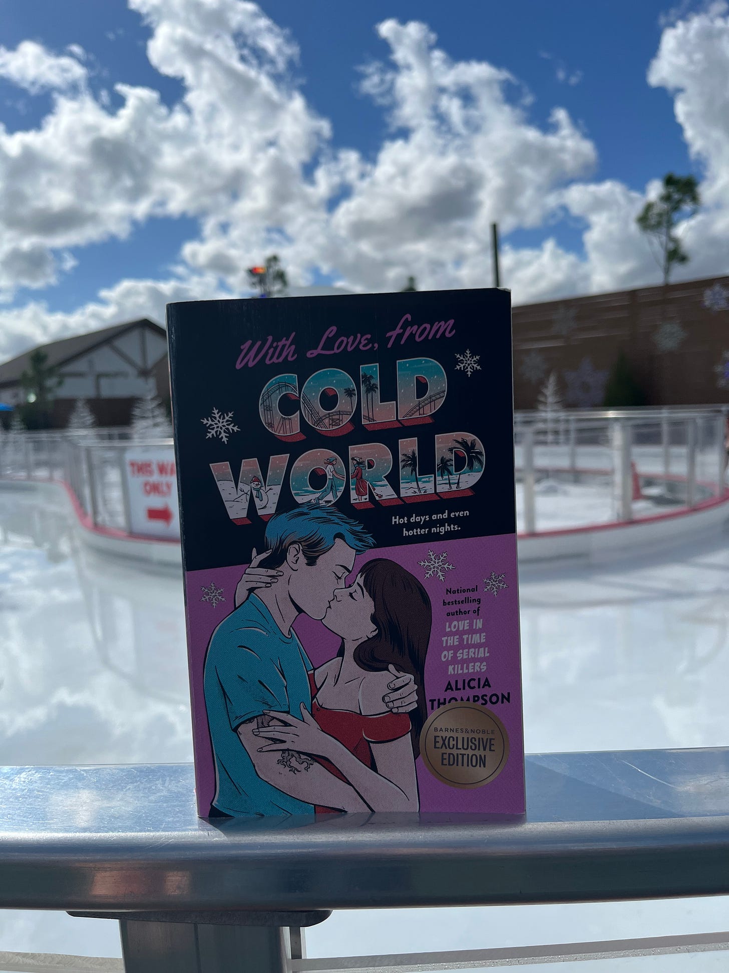 Picture of pink cover copy of WITH LOVE, FROM COLD WORLD propped up in front of the ice skating rink