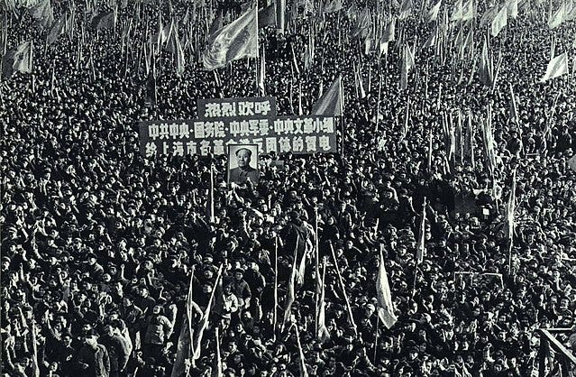 A black and white photograph of a huge crowd with flags