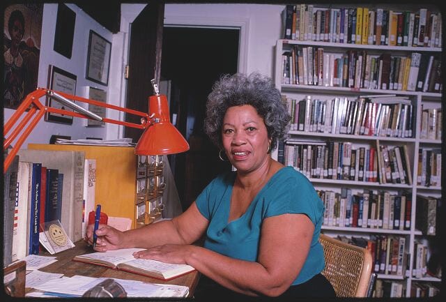 Author seated at a desk with a book open in front of her.