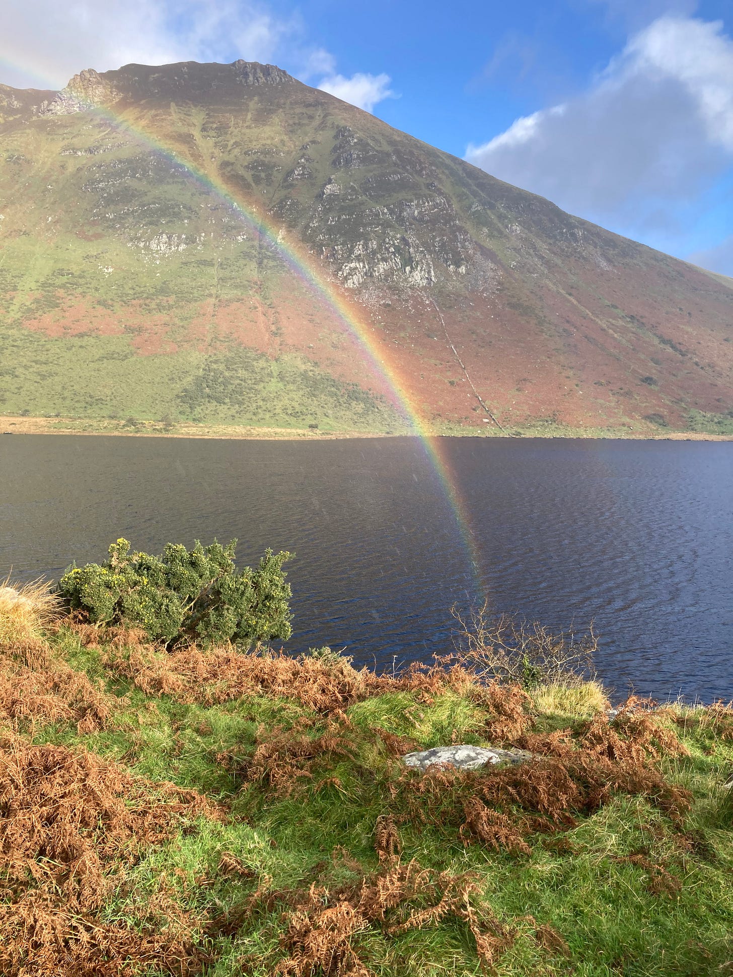 A rainbow over a mountain lake, sunlight after a rain shower