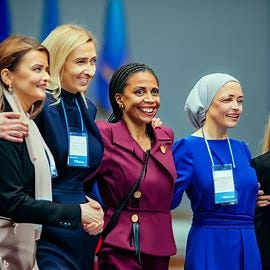 a group of female world leaders at a conference arm in arm. The women are all american high quality