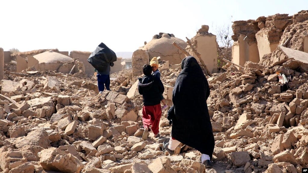 An Afghan woman walks with her children amid debris after a powerful earthquake in Herat province, western of Afghanistan, Oct. 15, 2023, in this handout photo released by Save the Children.