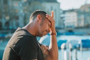 black man tired with grief by lake in city