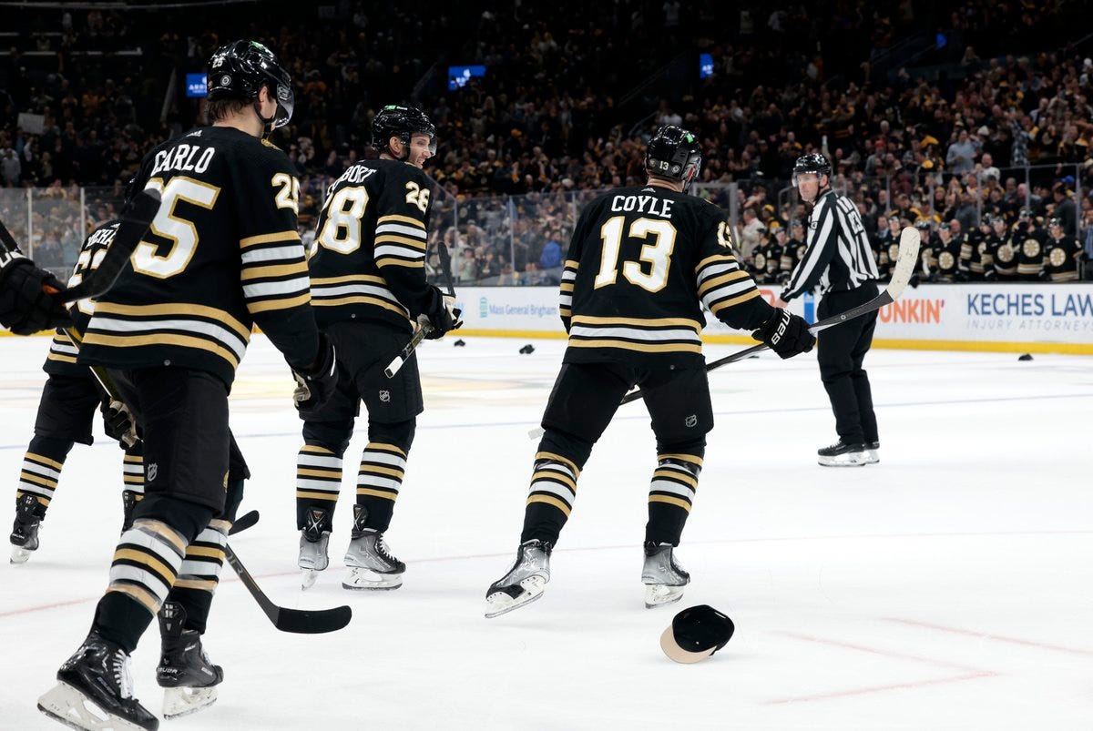 Brandon Carlo and Derek Forbort skate with Charlie Coyle as a hat sits on the ice following Coyle's hat trick.