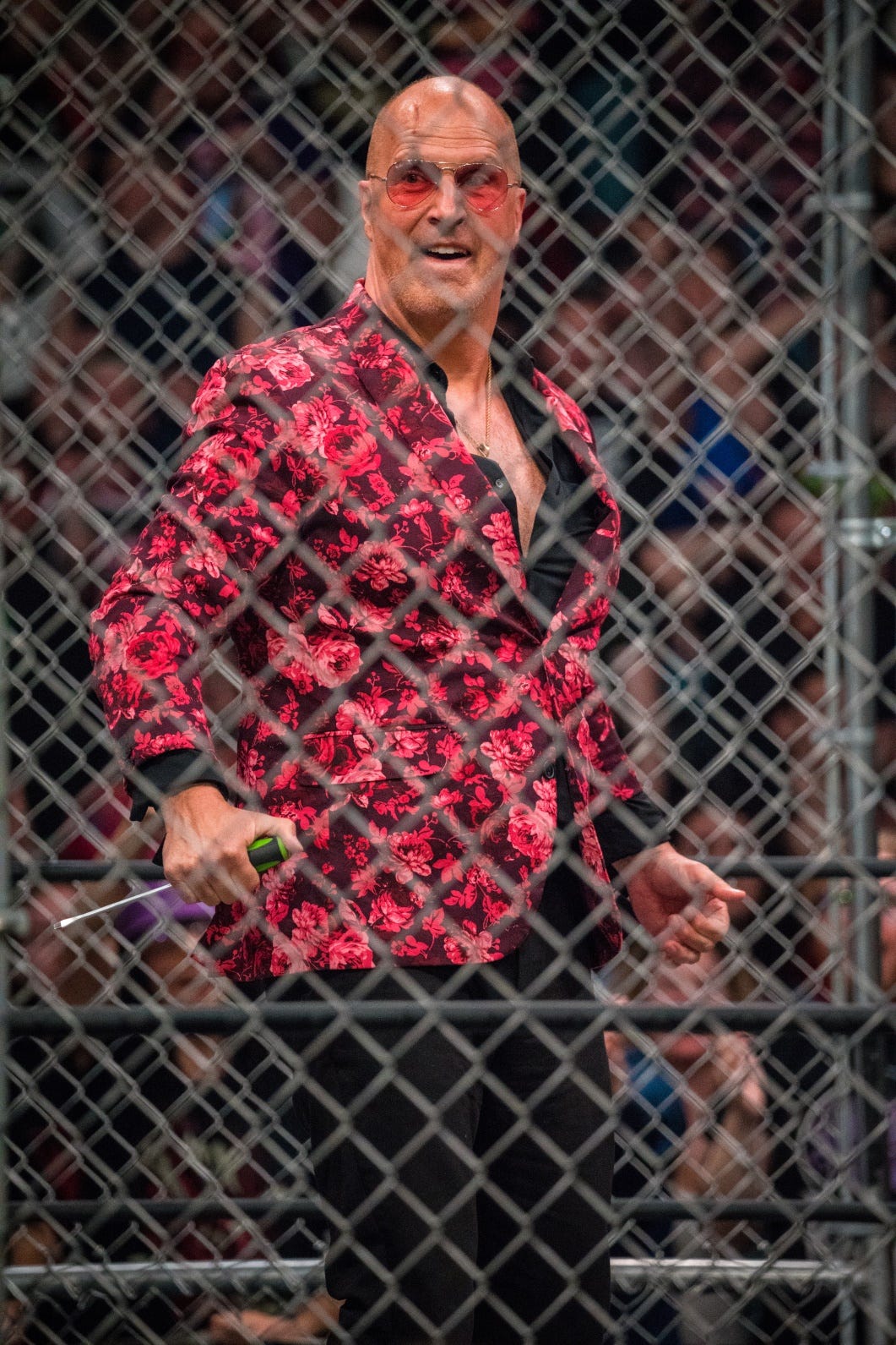 Don Callis laughs after having stabbed Kenny Omega with a screwdriver he still holds.