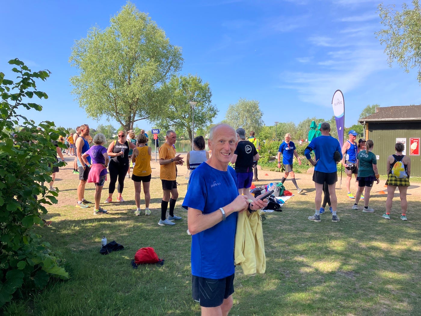 Grinning friend in front of chatting finishers at the end of the event