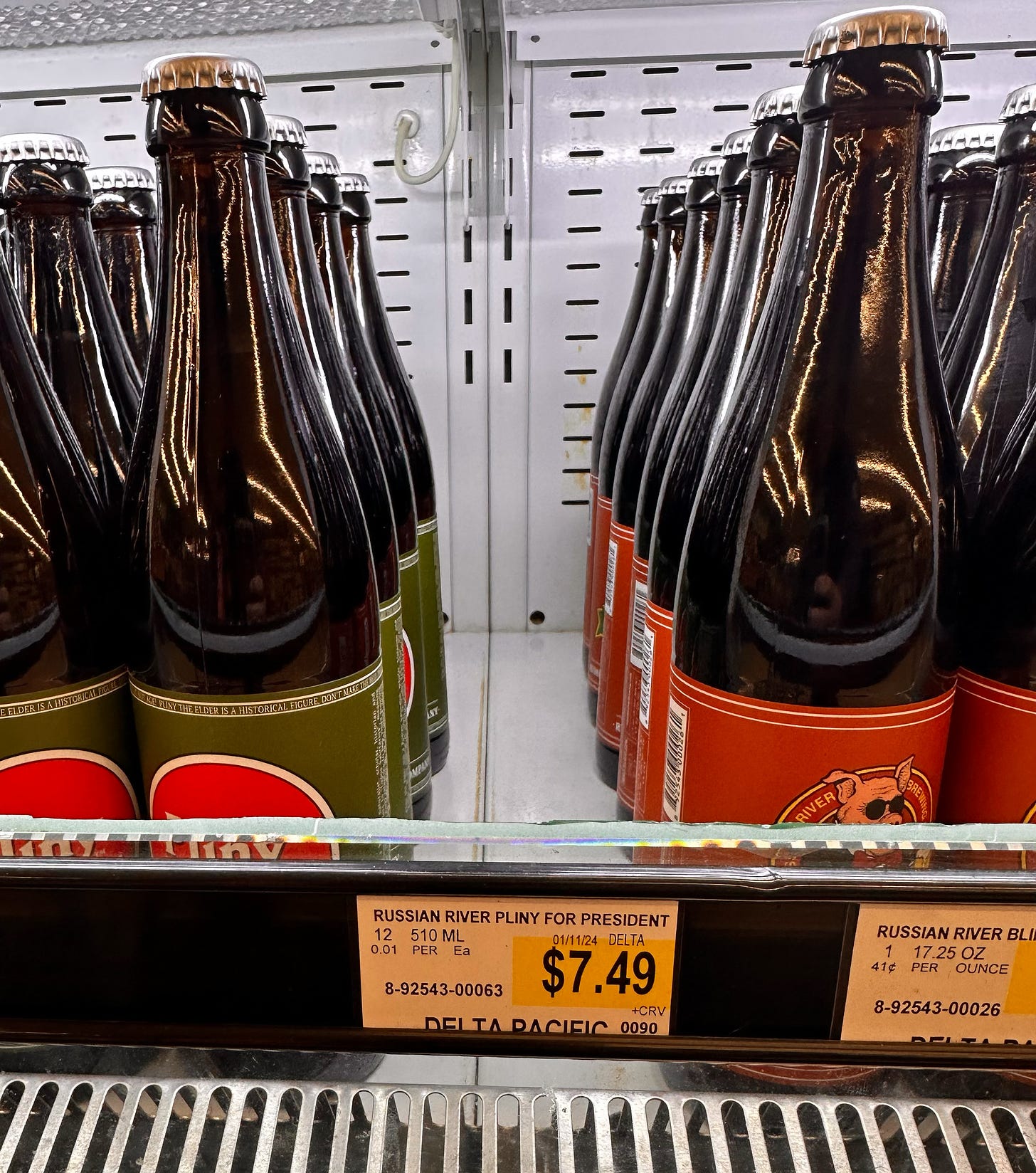 A grocery store shelf featuring Russian River Brewing beers Pliny The Elder and Bling Pig. But there is an empty space where they should be Pliny For President bottles.