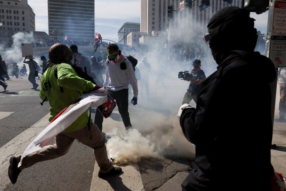 Demonstrators running from tear gas at a protest.