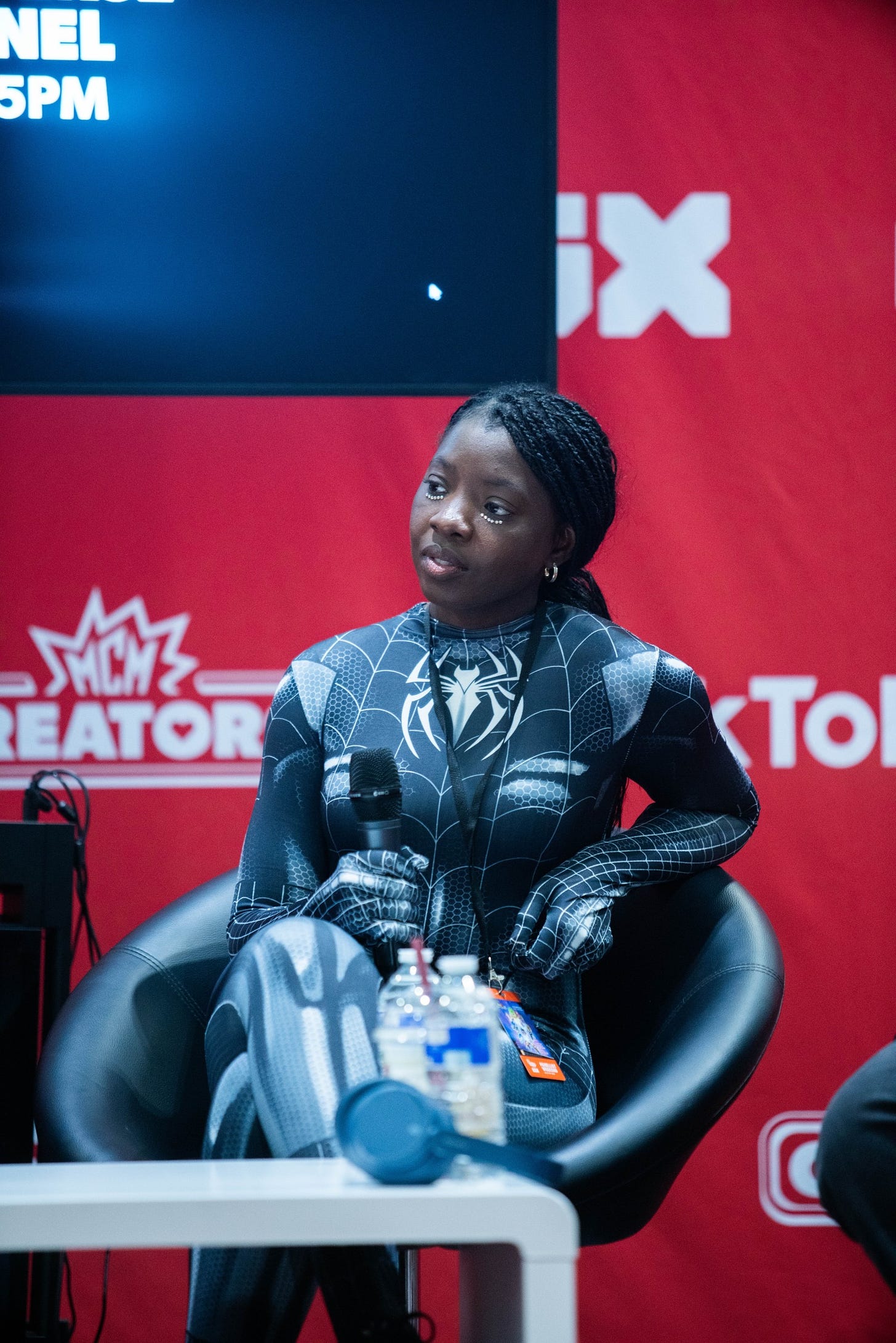 Myself dressed in the Black spiderman costume, holding a microphone and sat on stage for a panel at MCM Comic Con and EGX last week. Photography by Jon D Barker