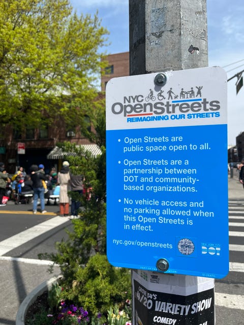 A street sign explains the rules of the open street, including that it is a public place, it is a partnership between DOT and community organizations, and that no vehicle access or parking is allowed during the open streets.