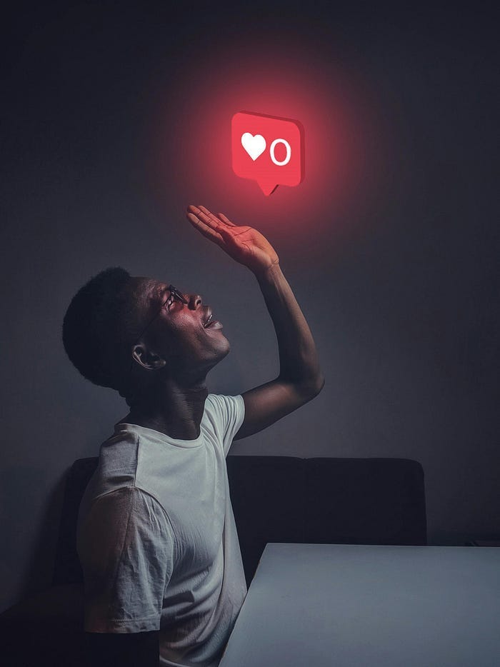 A man sitting at a table, reaching his hand up with a “0 likes” symbol on top of him.