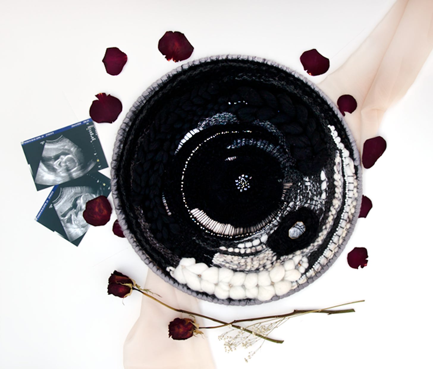 Black and white circular weaving surrounded by ultrasound images and rose petals