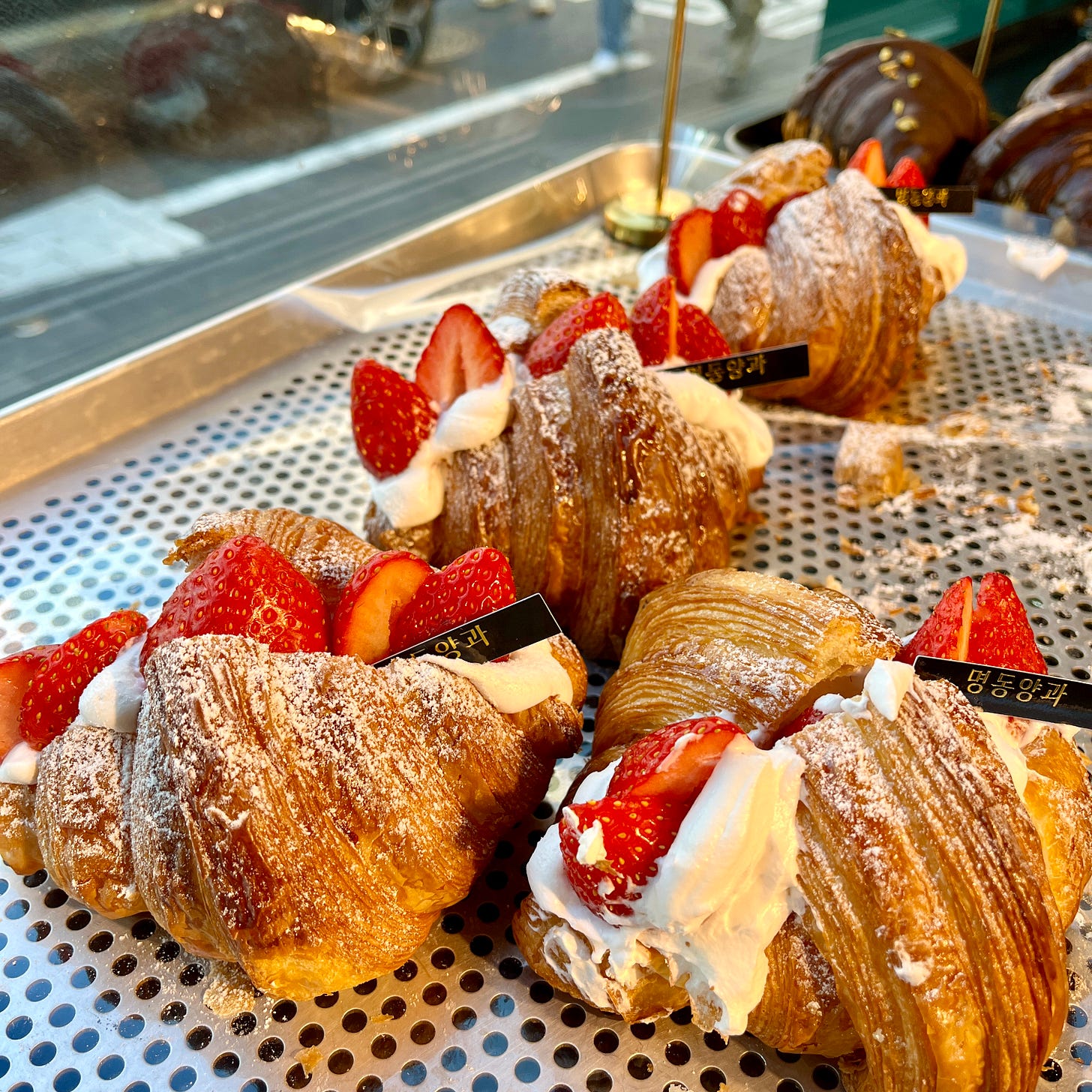 Platter of croissants stuffed to overflowing with whipped cream and sliced strawberries.