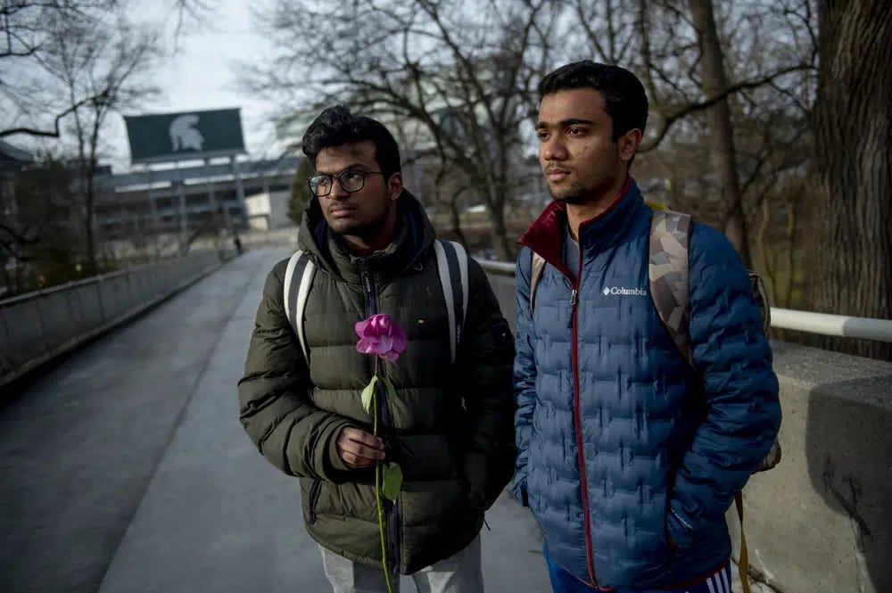 Michigan State international students Dheeraj Thota, left, and Chirag Bhansari, both freshman studying computer science, found a single rose on their walk to class as campus opens back up for the first day of classes on Monday, Feb. 20, 2023 at Michigan State University in East Lansing, Mich. Michigan State University is set to return to classes Monday, with officials saying they hope a return to familiarity may help the community heal. (Jake May/The Flint Journal via AP)