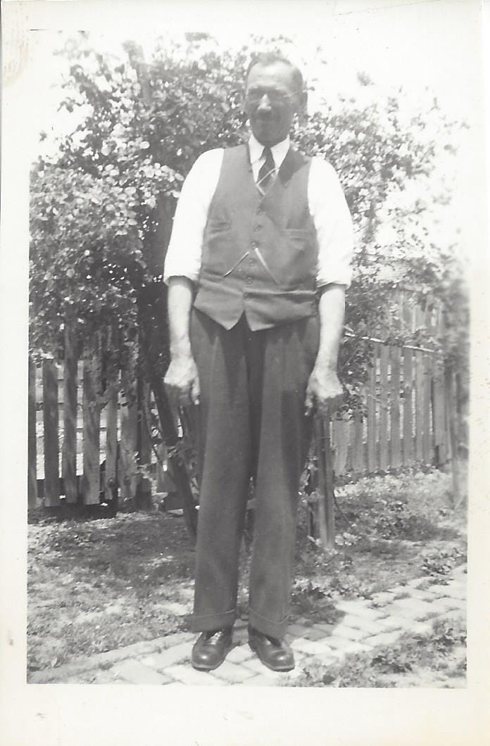 1920s-era man in his Sunday Best clothes standing in his backyard